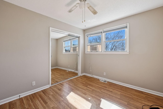 unfurnished bedroom featuring a textured ceiling, ceiling fan, wood finished floors, baseboards, and a closet