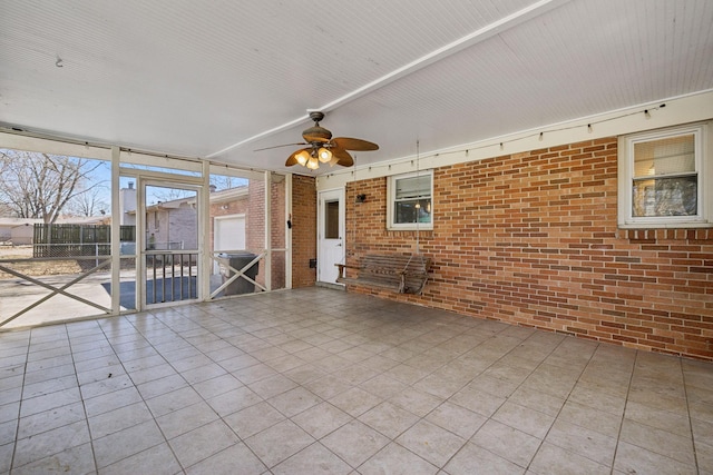 interior space featuring a ceiling fan and brick wall