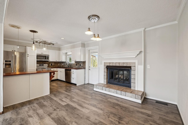 kitchen with a sink, visible vents, white cabinets, ornamental molding, and appliances with stainless steel finishes