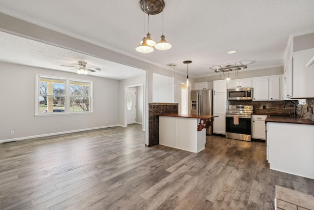 kitchen with a sink, open floor plan, appliances with stainless steel finishes, decorative backsplash, and dark countertops