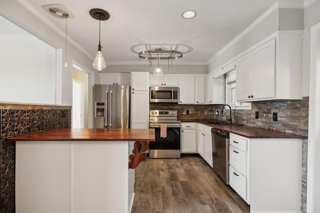 kitchen featuring visible vents, white cabinets, butcher block countertops, stainless steel appliances, and a sink