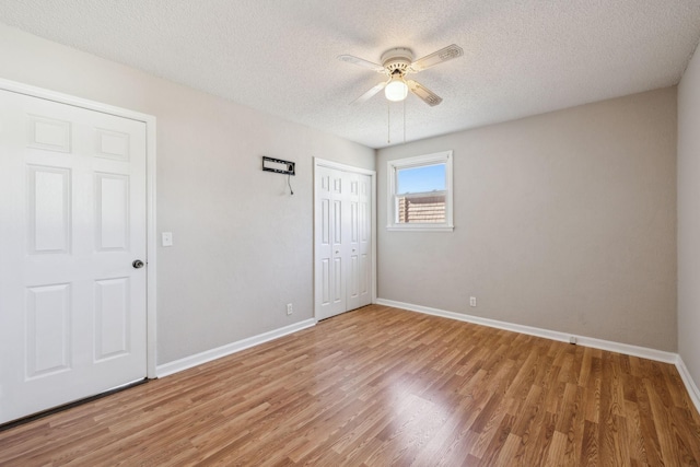 unfurnished bedroom with a textured ceiling, baseboards, and wood finished floors