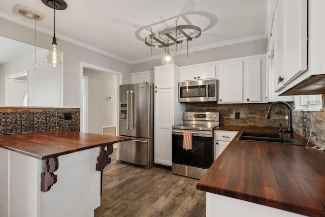 kitchen with visible vents, wooden counters, decorative backsplash, appliances with stainless steel finishes, and a sink