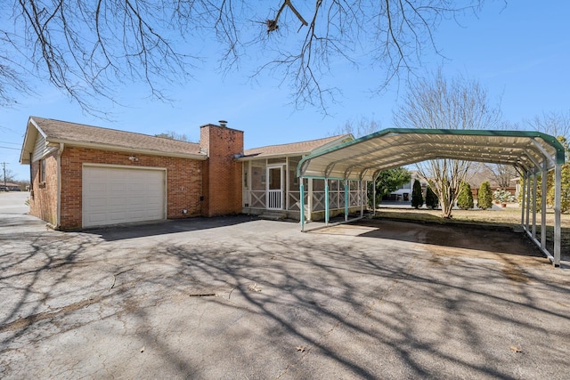 exterior space with a carport, brick siding, a chimney, and aphalt driveway