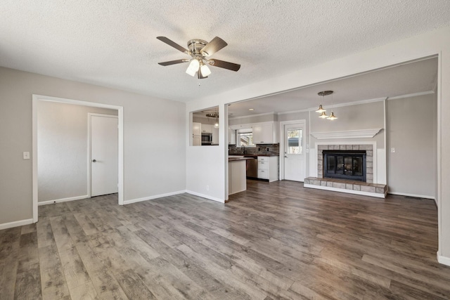 unfurnished living room featuring dark wood-style flooring, a tile fireplace, a ceiling fan, and baseboards