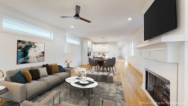 living area with baseboards, a fireplace, light wood-style flooring, and recessed lighting