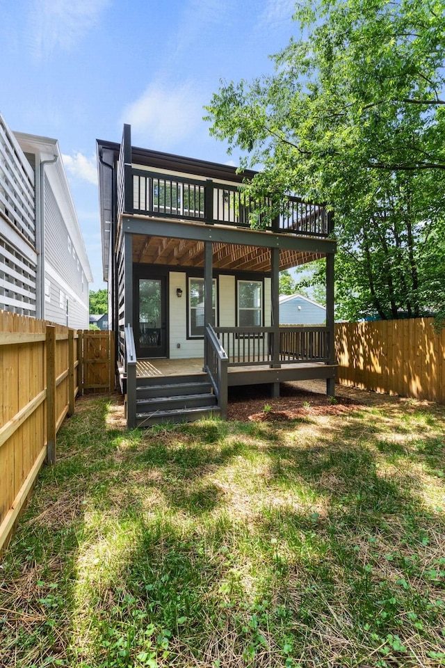 rear view of house featuring a fenced backyard, a lawn, and a deck