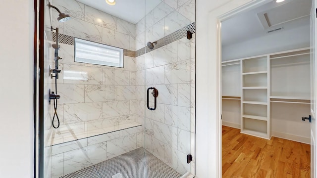 full bath featuring a stall shower, visible vents, a spacious closet, and wood finished floors