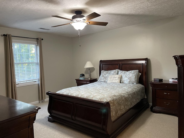 bedroom with ceiling fan, a textured ceiling, light carpet, visible vents, and baseboards