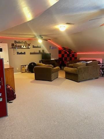 carpeted cinema room featuring ceiling fan, vaulted ceiling, and a textured ceiling