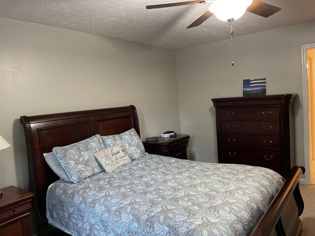 carpeted bedroom with a ceiling fan and a textured ceiling