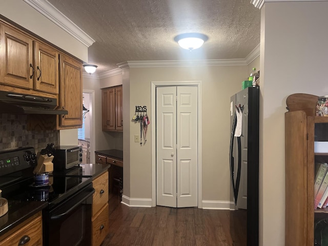 kitchen with crown molding, dark countertops, black electric range oven, freestanding refrigerator, and under cabinet range hood