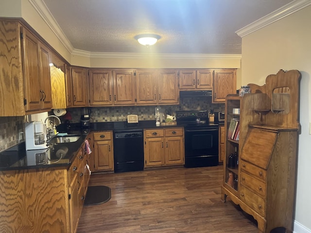 kitchen with dark wood finished floors, dark countertops, ornamental molding, a sink, and black appliances