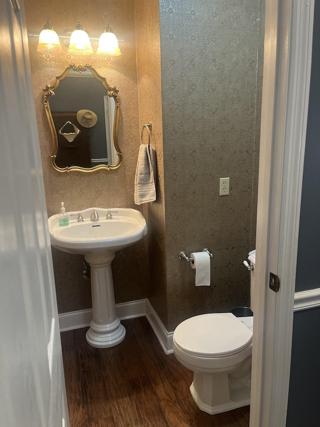 half bath featuring toilet, baseboards, and wood finished floors