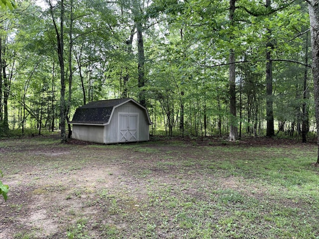 view of yard featuring a forest view, a shed, and an outdoor structure