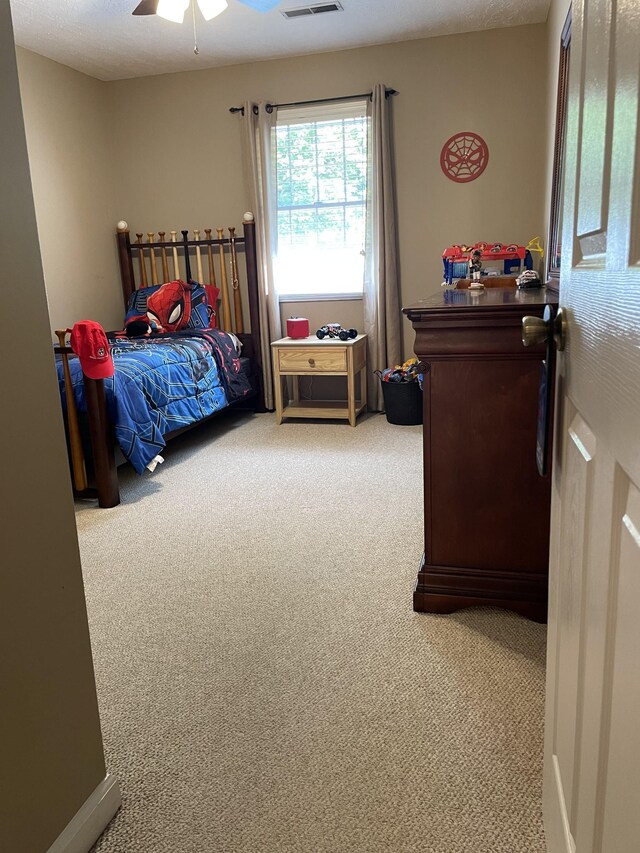 carpeted bedroom featuring ceiling fan and visible vents