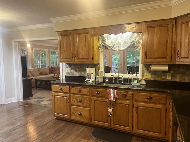 kitchen featuring brown cabinets, dark countertops, a sink, and crown molding