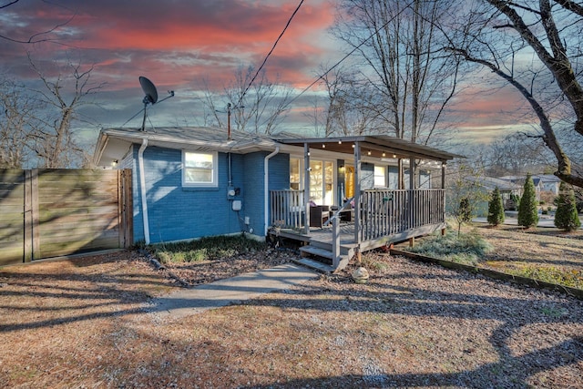 view of front of property featuring covered porch, a gate, and brick siding