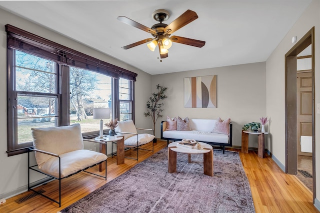 living area featuring ceiling fan, baseboards, and wood finished floors