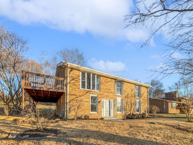 rear view of property featuring brick siding and a wooden deck