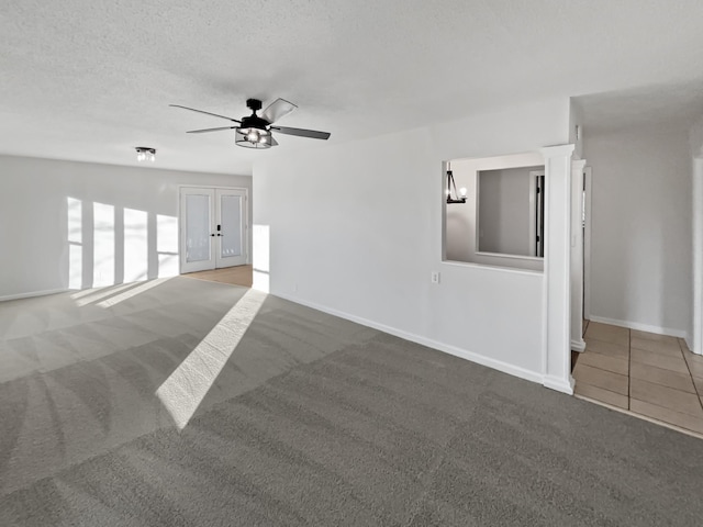 unfurnished living room featuring baseboards, ceiling fan, tile patterned flooring, a textured ceiling, and carpet flooring