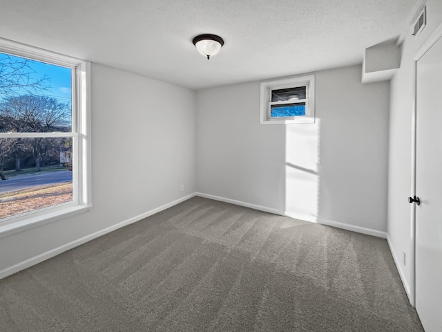 carpeted empty room with baseboards, a textured ceiling, and a healthy amount of sunlight