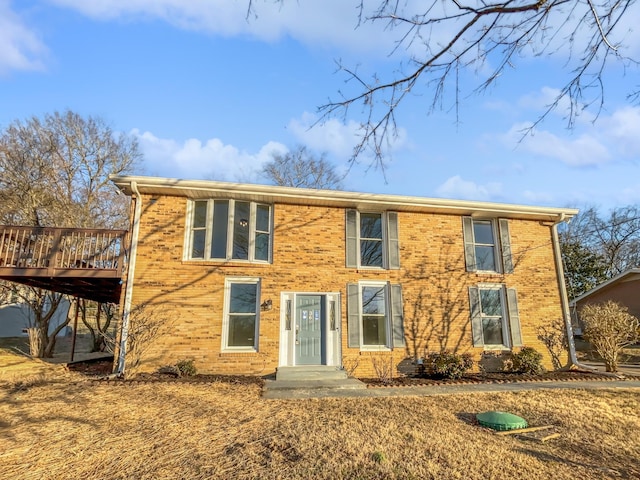 colonial-style house featuring a wooden deck and brick siding