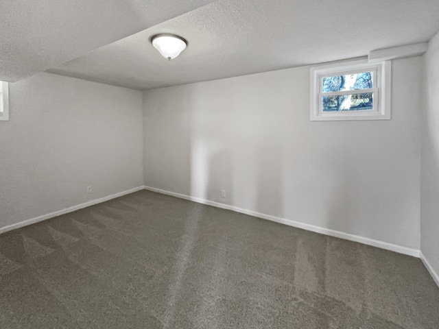 basement featuring carpet floors, baseboards, and a textured ceiling