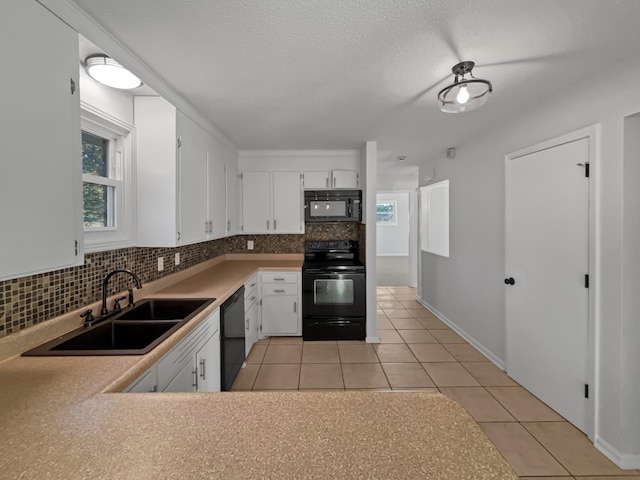 kitchen with tasteful backsplash, light tile patterned flooring, a sink, white cabinetry, and black appliances