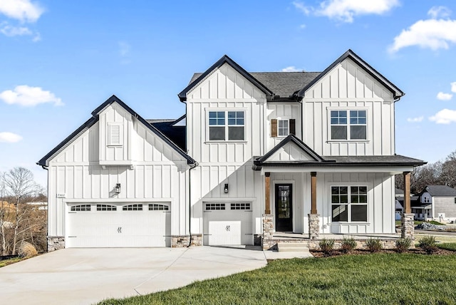 modern farmhouse style home with a porch, stone siding, board and batten siding, and concrete driveway