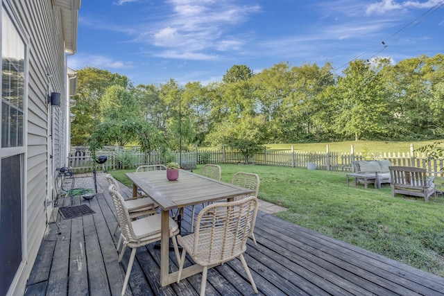 wooden terrace featuring outdoor dining space, a lawn, and a fenced backyard