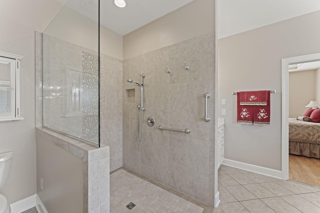 ensuite bathroom featuring toilet, connected bathroom, a walk in shower, tile patterned flooring, and baseboards