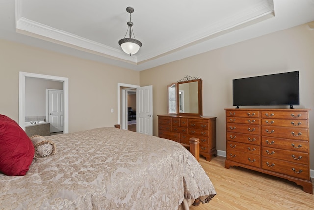 bedroom with light wood-style floors, connected bathroom, a raised ceiling, and crown molding