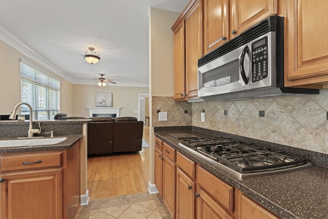 kitchen featuring brown cabinets, crown molding, stainless steel appliances, and a sink