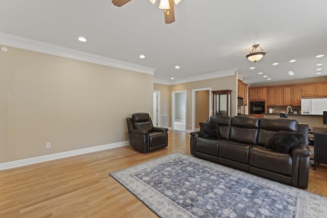 living room with baseboards, recessed lighting, light wood-style flooring, and crown molding