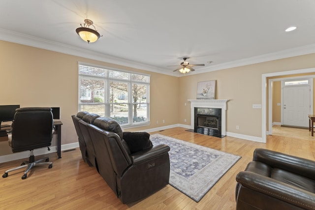 living area featuring light wood-style floors, baseboards, a fireplace, and ornamental molding