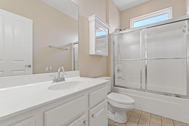 bathroom with combined bath / shower with glass door, vanity, toilet, and tile patterned floors