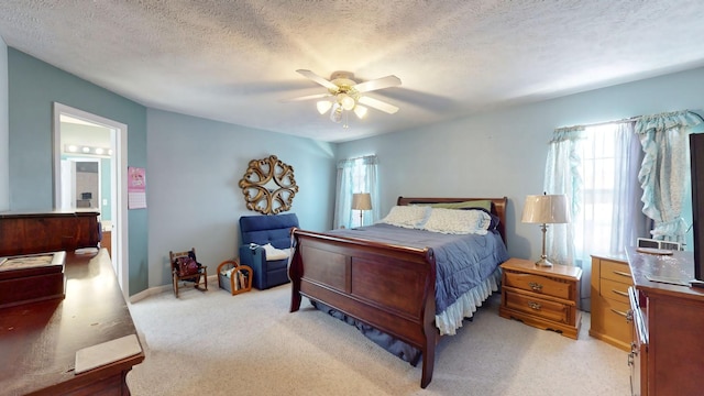 bedroom with a ceiling fan, light colored carpet, connected bathroom, and a textured ceiling