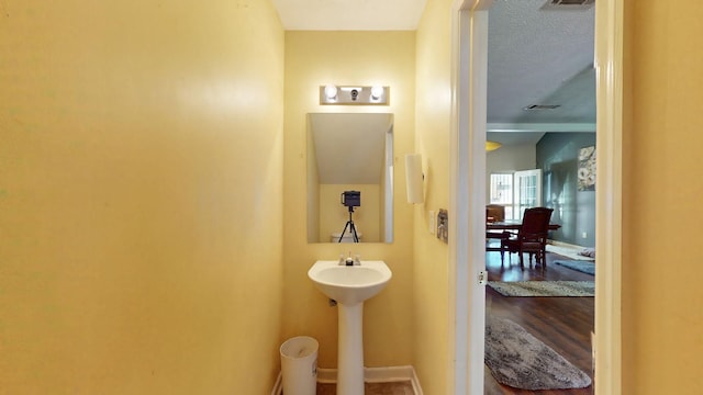 bathroom featuring visible vents, a textured ceiling, and baseboards