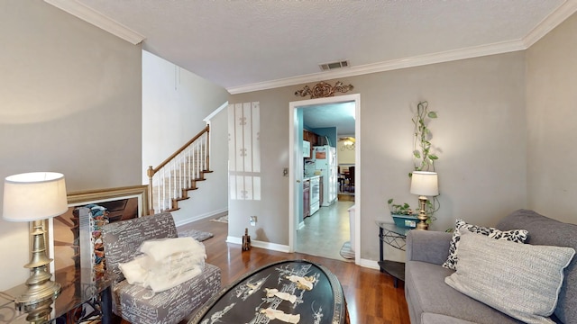 interior space featuring wood finished floors, visible vents, baseboards, stairs, and ornamental molding