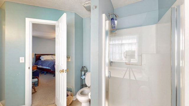 ensuite bathroom featuring a stall shower, a textured ceiling, and connected bathroom