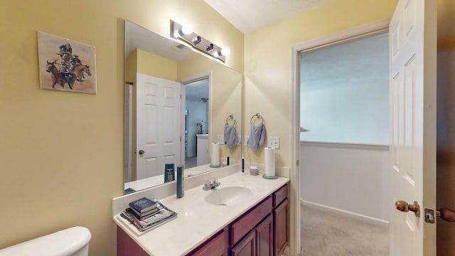 bathroom featuring toilet, baseboards, and vanity