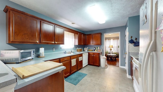 kitchen with white appliances, a toaster, light countertops, and a sink