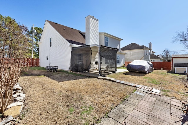 back of property with a chimney, a patio area, and a fenced backyard