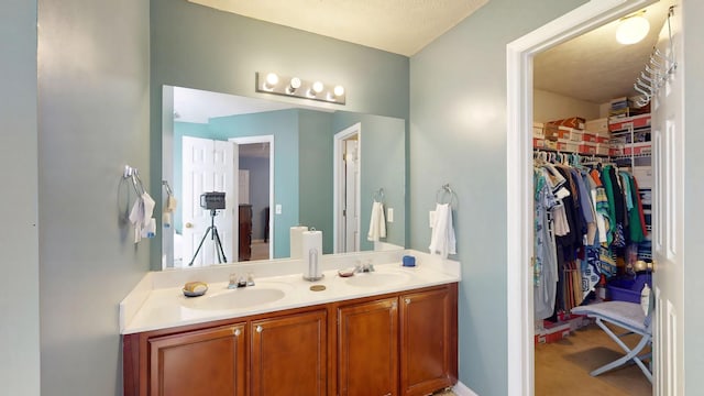 full bathroom with double vanity, a sink, and a walk in closet