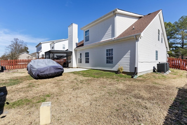 rear view of property featuring a lawn, a patio area, cooling unit, and fence