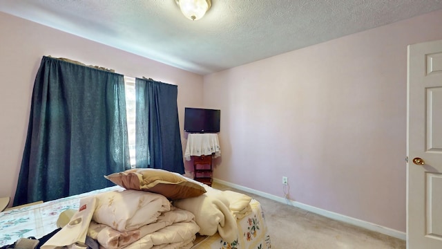 bedroom with light carpet, a textured ceiling, and baseboards