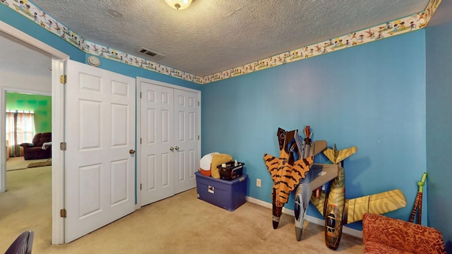 playroom featuring baseboards, a textured ceiling, visible vents, and carpet flooring