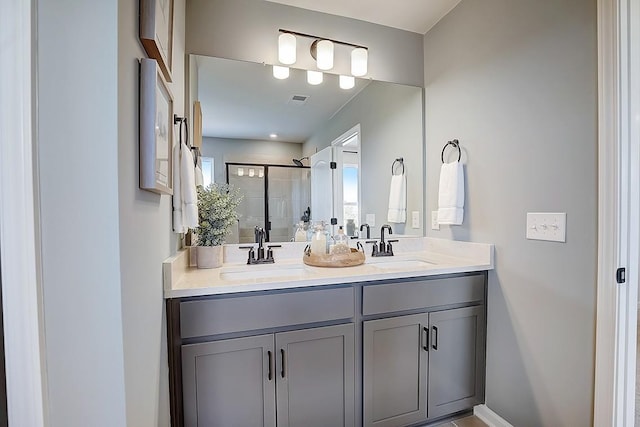 bathroom with double vanity, a shower stall, visible vents, and a sink