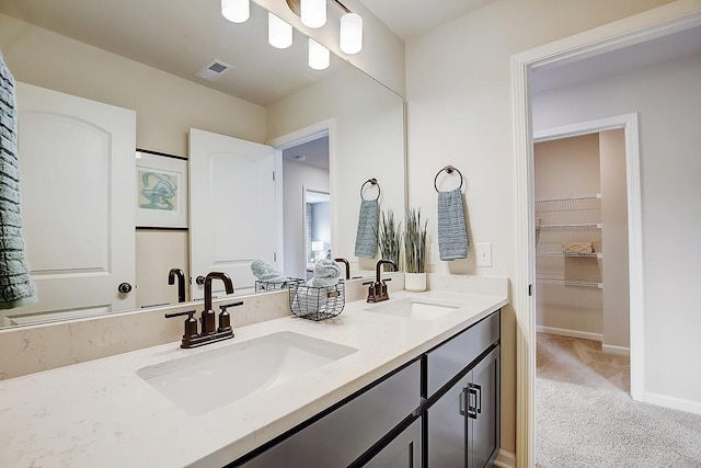 bathroom with double vanity, a sink, visible vents, and baseboards